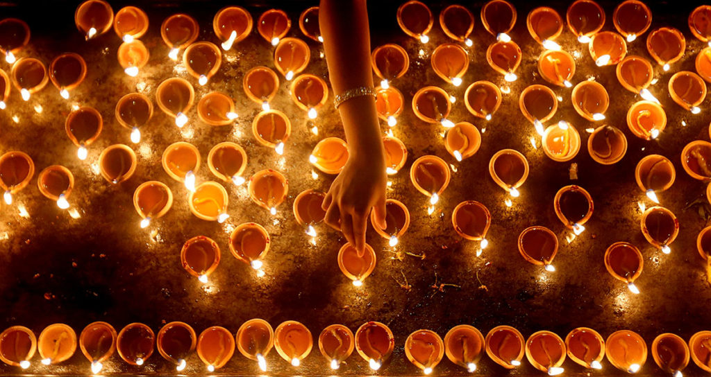 A devotee lights oil lamps at a religious ceremony during the Diwali or Deepavali festival at a Hindu temple in Colombo